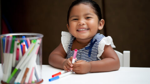 Children engaged in creative play activities, including painting, building with blocks, and dress-up